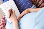Pregnant woman listing baby names at home in the living room