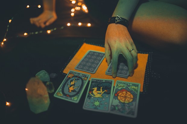 A woman deals tarot cards in the dark. Stock photo.