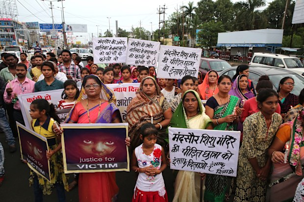 Indian people hold posters and candles during a candle light march to protest against the rape of a seven-year-old girl (EPA/SANJEEV GUPTA).