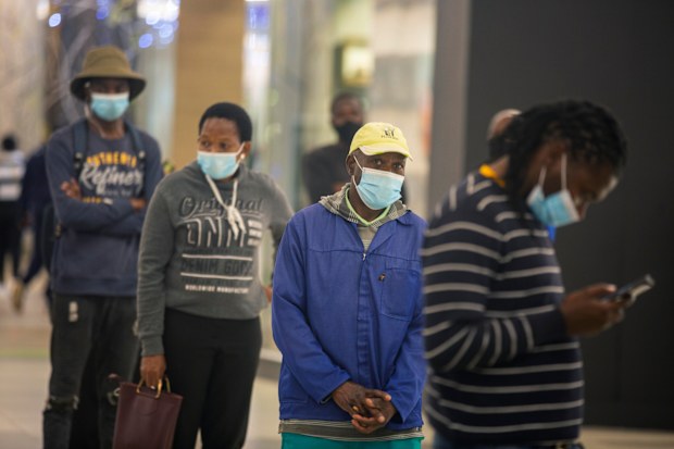 People lineup to get cash at a bank in a shopping mall in Johannesburg, South Africa, Friday Nov. 26, 2021. 