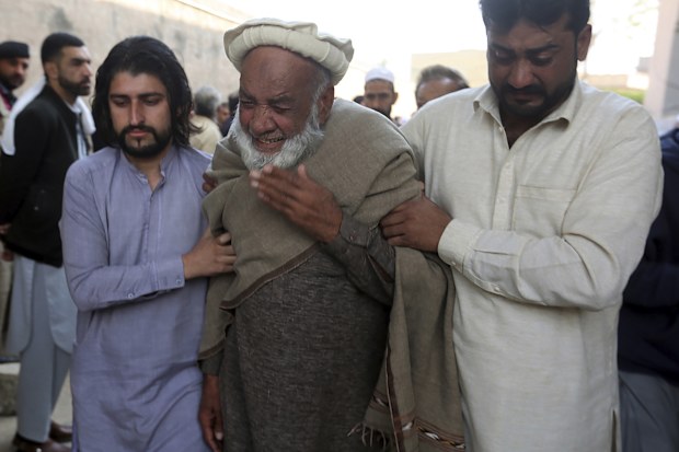 People mourn over the death of their relative, a  police officer killed in the Monday's suicide bombing inside a mosque, in Peshawar, Pakistan.