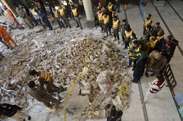 Rescue workers gather as they conduct an operation to clear the rubble and find the bodies at the site of Monday's suicide bombing, in Peshawar, Pakistan.