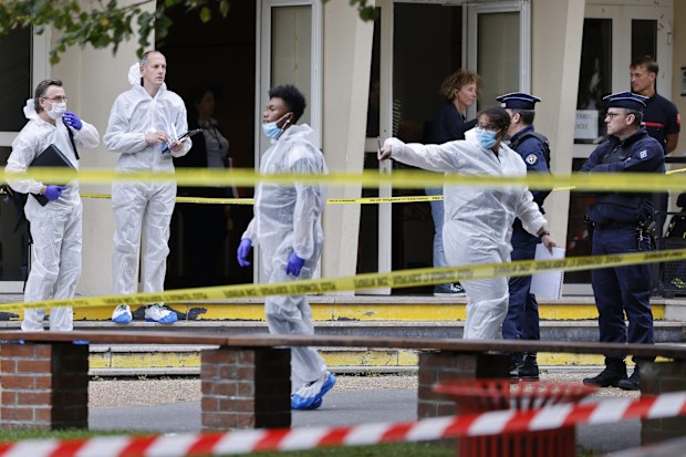 French police officers from the forensic service stand in front of the Gambetta high school in Arras, northeastern France, after a man armed with a knife killed a teacher and wounded another teacher and a security guard, an attack being investigated as potential terrorism, Friday Oct. 13, 2023.