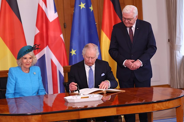King Charles III prepares to sign the official guest book as Camilla, Queen Consort and German President Frank-Walter Steinmeier look on at Schloss Bellevue presidential palace on the first day of the state visit to Germany on March 29, 2023 in Berlin, Germany.