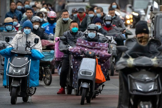 Commuters wearing face masks ride scooters along a street in the central business district in Beijing, Friday, Oct. 28, 2022 