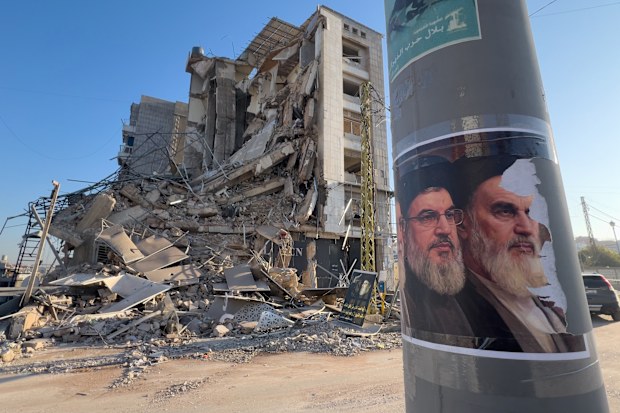 Portraits of late Hezbollah leader Sayyed Hassan Nasrallah and the late Iranian revolutionary founder Ayatollah Khomeini, are seen in front of a destroyed building that housed a branch of Al-Qard Al-Hassan, a non-bank financial institution run by Hezbollah, which was hit by an Israeli airstrike in Dahiyeh, Beirut's southern suburbs, Lebanon, Tuesday, March 10, 2026. (AP Photo/Hussein Malla)