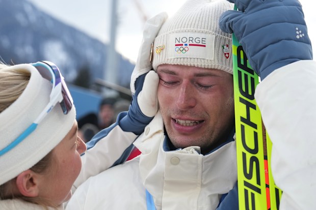 Sturla Holm Laegreid, of Norway, after winning bronze as teammate Ingrid Landmark Tandrevold comforts him after the men's 20-kilometer individual biathlon race at the 2026 Winter Olympics in Anterselva, Italy, Feb. 10, 2026.