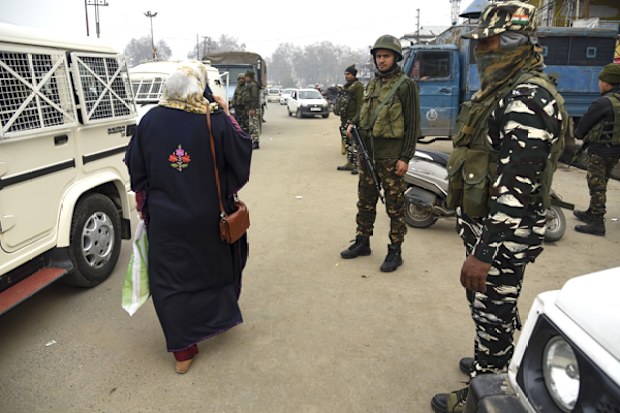 A Kashmiri woman walks past Indian Paramilitary forces standing guard close to the site of a blast in Indian controlled Kashmir. At least three people were wounded in a low-intensity blast in Srinagar city, on November 26.