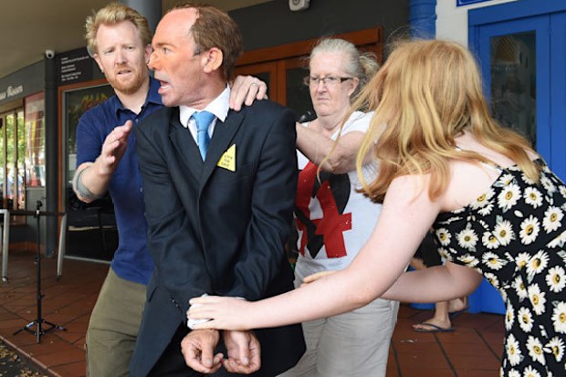 A man dressed as Tony Abbott is hand cuffed during a mock arrest for "attempted eco-cide" at a protest event in Brisbane. (AAP)