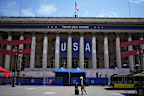 A man pulls his luggage in front of Team USA House, Friday, July 19, 2024, in Paris, France. Team USA House is set up at the former Paris stock exchange and will offer activities and a base to cheer on and celebrate Team USA at the Olympic Games. (AP Photo/David Goldman)