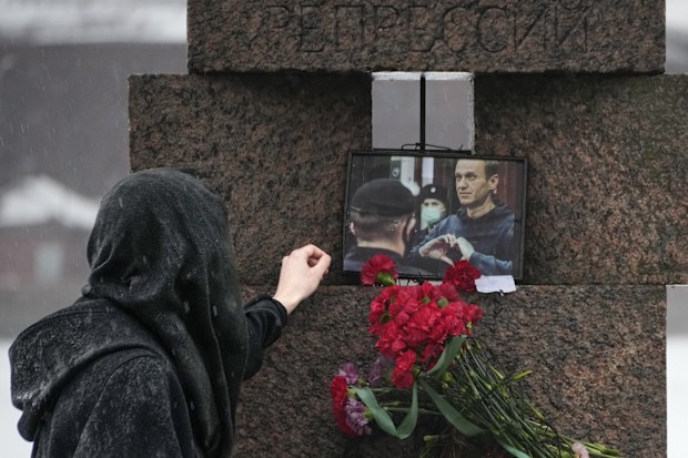 A woman touches a photo of Alexei Navalny after laying flowers paying the last respect to him at the Memorial to Victims of Political Repression in St. Petersburg, Russia on Saturday, Feb. 17, 2024