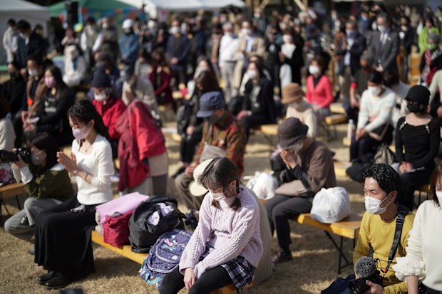 Visitors pray for a minute of silence for the victims of the March 11, 2011 earthquake and tsunami during a special memorial event Friday, March 11, 2022, in Tokyo, Japan