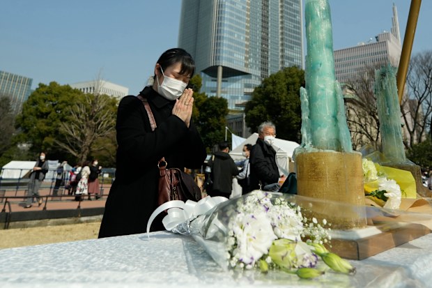A visitor prays at a makeshift altar to mourn for the victims of the March 11, 2011 earthquake and tsunami during a special memorial event Friday, March 11, 2022, in Tokyo, Japan 