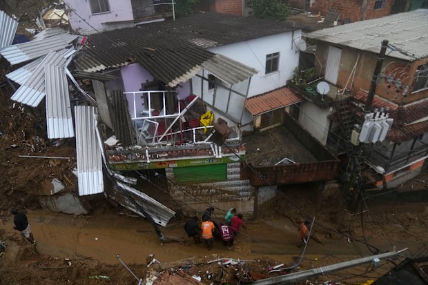 Residents and volunteers remove the body of a landslide victim in Petropolis, Brazil, Wednesday, Feb. 16, 2022. 