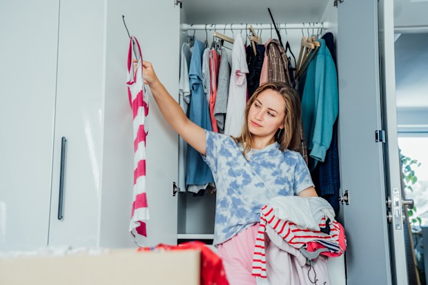 Woman selecting clothes from her wardrobe for donating to a Charity shop
