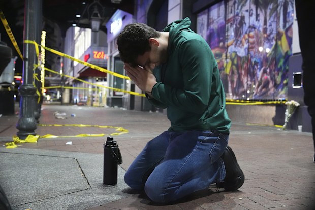 Matthias Hauswirth of New Orleans prays on the street near the scene where a vehicle drove into a crowd on New Orleans' Canal and Bourbon streets