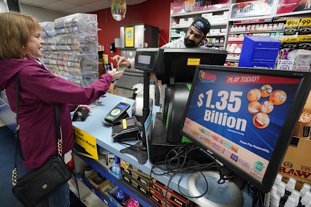 A Mega Millions sign displays the estimated jackpot of $1.35 billion as a customer purchases a Mega Millions ticket at the Cranberry Super Mini Mart in Cranberry, Pa., Thursday, Jan. 12, 2023. 