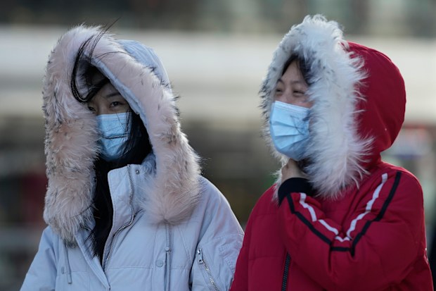 Women wearing masks to curb the spread of the coronavirus walks against strong wind in Beijing, China, Thursday, Dec. 30, 2021. (AP Photo/Ng Han Guan)