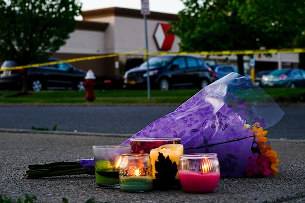 Flowers and candles lay outside the scene of a shooting at a supermarket, in Buffalo, N.Y., Sunday, May 15, 2022.  