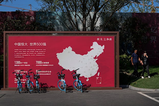 People walk by a map showing Evergrande development projects in China at an Evergrande new housing development in Beijing in September.