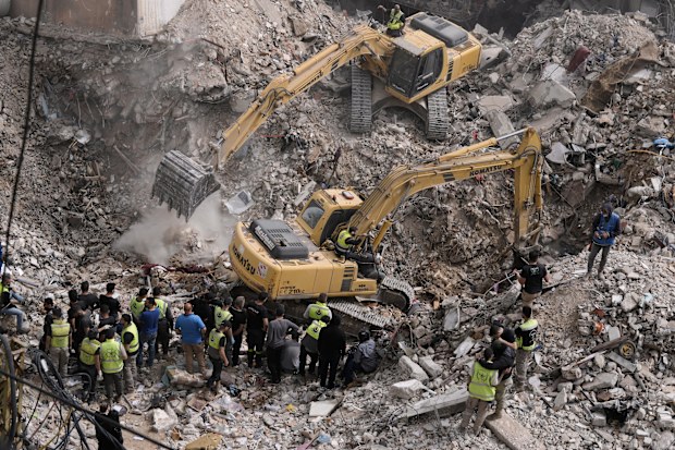 Excavators remove the rubble from destroyed buildings that were hit by Israeli airstrikes on Thursday, as rescuers search for victims in the city of Tyre, southern Lebanon