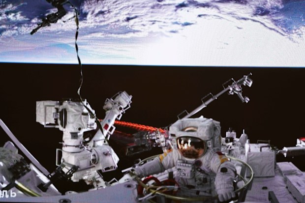 Chinese astronaut Cai Xuzhe exiting the station lab module Wentian to conduct extravehicular activities.