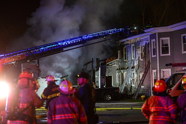 Fire departments work to extinguish a fire after a single-engine plane crashed near the building Friday, Oct. 21, 2022, in Keene, N.H.  