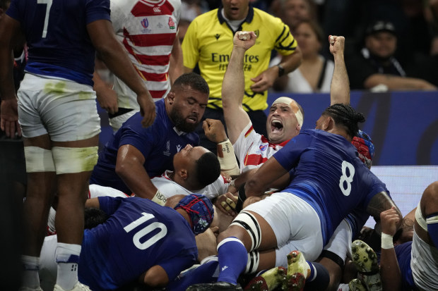 Japan's Craig Millar, centre, celebrates after his captain Kazuki Himeno scores a try during in their match against Samoa.