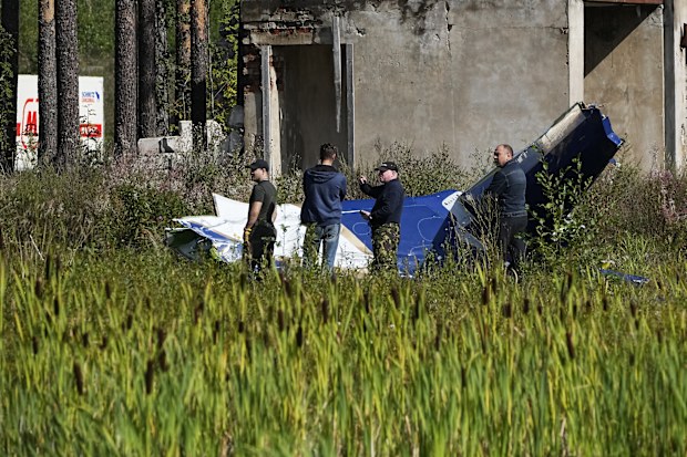 Russian servicemen inspect a part of a crashed private jet near the village of Kuzhenkino, Tver region, Russia, Thursday, Aug. 24, 2023