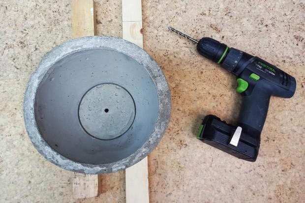 Hole drilled in concrete plant pot during DIY project.