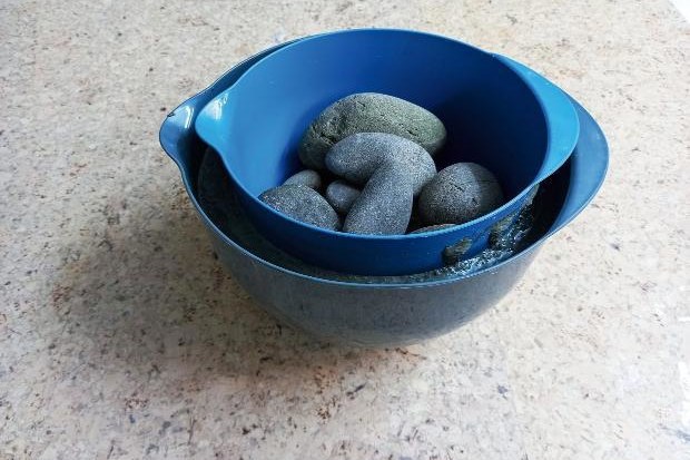 Mould weighted down with rocks during DIY concrete plant pot project.