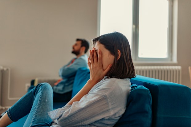 Unhappy Couple After an Argument in the Living Room at Home. Sad Pensive Young Girl Thinking of Relationships Problems Sitting on Sofa With Offended Boyfriend, Conflicts in Marriage, Upset Couple After Fight Dispute, Making Decision of Breaking Up Get Divorced