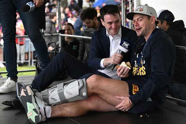 Lachie Neale is interviewed in his moon boot on the day after the grand final.