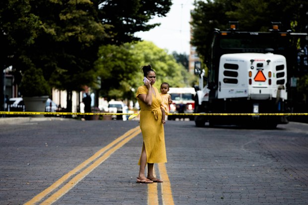 A woman holding a baby stands outside the Oregon District crime scene the 400 block of E. Fifth Street in Dayton , Ohio. Ten people where killed, including the gunman, and 26 injured in a mass shooting.
