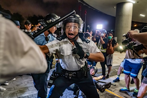 Police officers charge toward protesters after a rally against the extradition law proposal at the Central Government Complex on June 10 in Hong Kong.