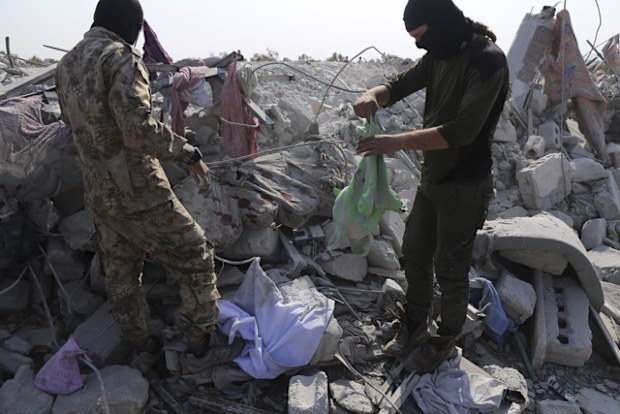 After the American troops retreated, US fighter jets fired six rockets at Abu Bakr al-Baghdadi's house, leveling it. This photo shows people standing on piles of rubble, after US special forces left the site.