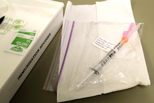 A syringe containing the first shot given in the first-stage safety study clinical trial of a potential vaccine for COVID-19, the disease caused by the new coronavirus, rests on a table