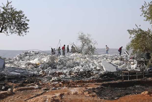 People look at a destroyed house near the village of Barisha, in Idlib province, Syria, after an operation by the US military which targeted and killed Abu Bakr al-Baghdadi, the shadowy leader of the Islamic State group.