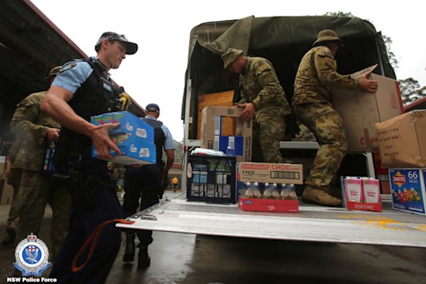 NSW police officers and the ADF unload a truck of supplies.