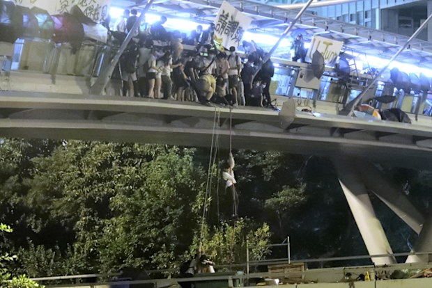 Protesters use a rope to lower themselves from a pedestrian bridge to waiting motorbikes in order to escape from Hong Kong Polytechnic University and the police in Hong Kong.