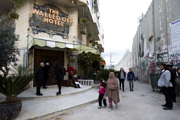 People pass by the "The Walled Off Hotel" and the Israeli security barrier in the West Bank city of Bethlehem. The nine-room hotel claims to have the worst views in the world. 