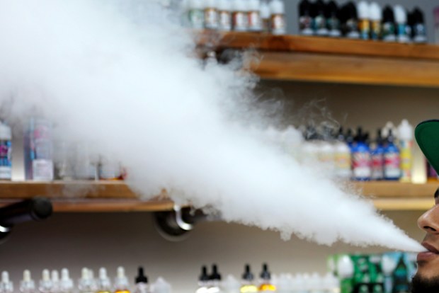A salesman at a vape shop exhales while using an e-cigarette in Maine, USA.