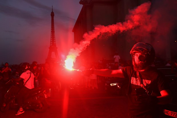 A man holds a flare as PSG supporters celebrate in Paris.