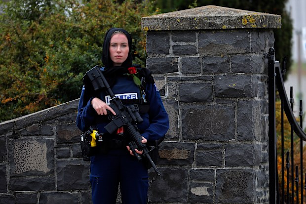 A police officer stands guard with a rose at the service for a victim of the attacks.