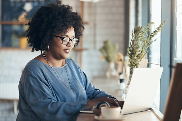 A businesswoman sitting and working on her laptop in a coffee shop during the day