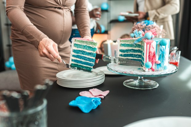 Close-up shot of an expectant mother sharing cake slices with a group of friends at a gender reveal party.