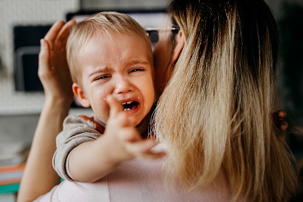 Cute little baby boy crying in his mother arms