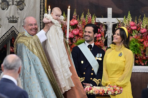 Chief Chaplain, Bishop Johan Dalman holds up Princess Ines after baptising her as Sweden's Prince Carl Philip, second from right, and Princess Sofia look on, in Drottningholm Palace Chapel, Stockholm, Friday, June 13, 2025. (Anders Wiklund/TT via AP)