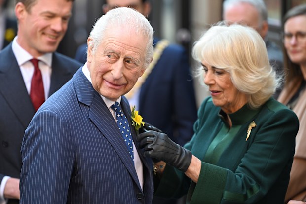 BELFAST, NORTHERN IRELAND - MARCH 19: Queen Camilla ties a flower on the lapel of King Charles III during a visit to Commercial Court as part of an official visit to Northern Ireland on March 19, 2025 in Belfast, Northern Ireland.  (Photo by Stuart C. Wilson/Getty Images)
