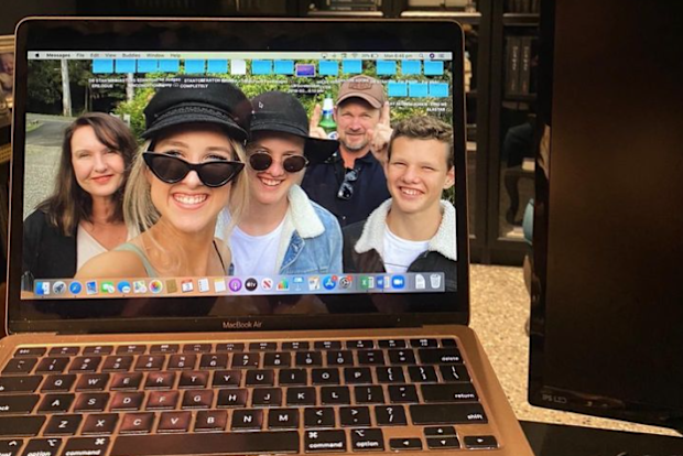 T L Swan's home writing setup, with a picture of her family as her laptop background.